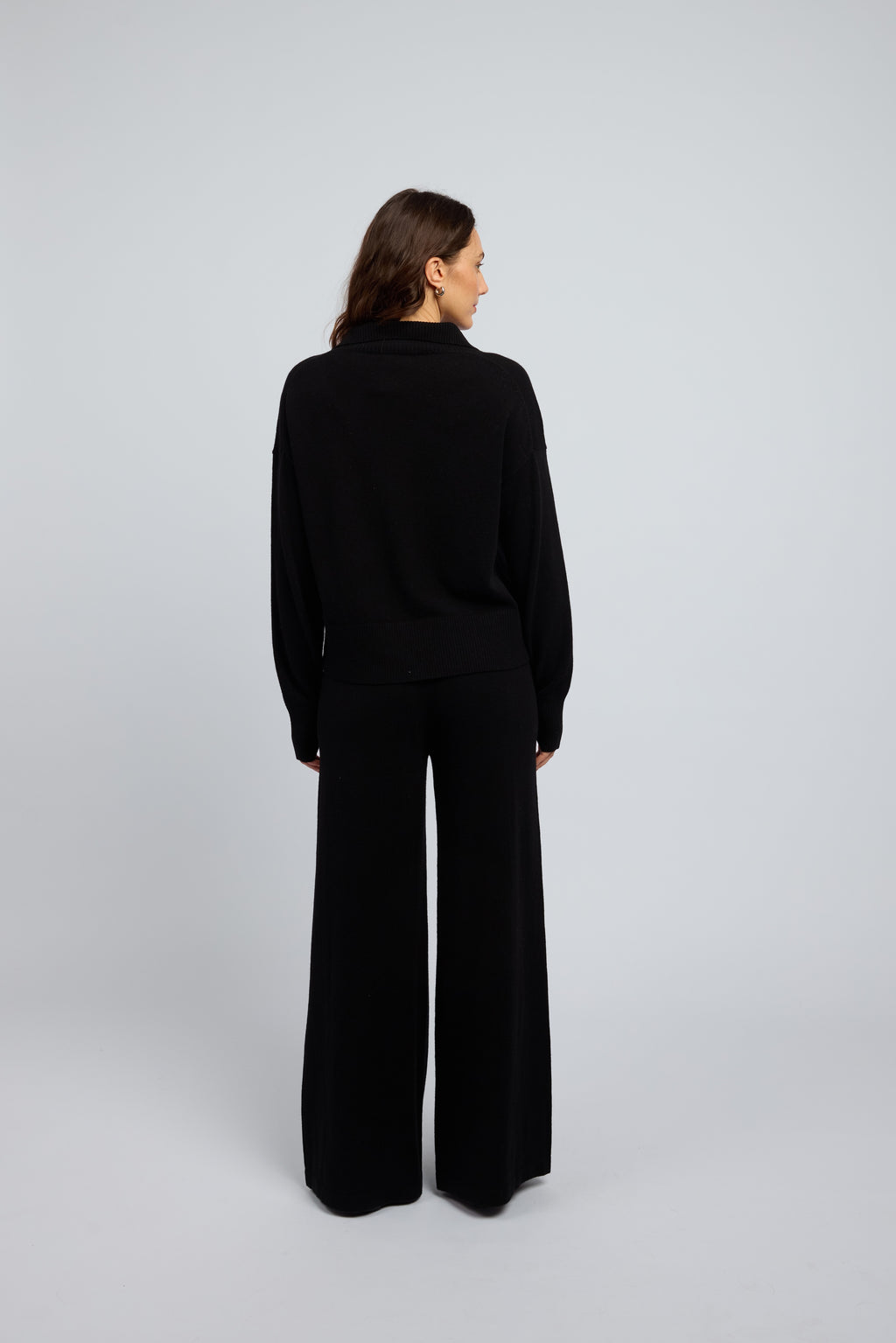 Woman wearing a cashmere set in black, matching pants and zip through jumper with a folded down collar