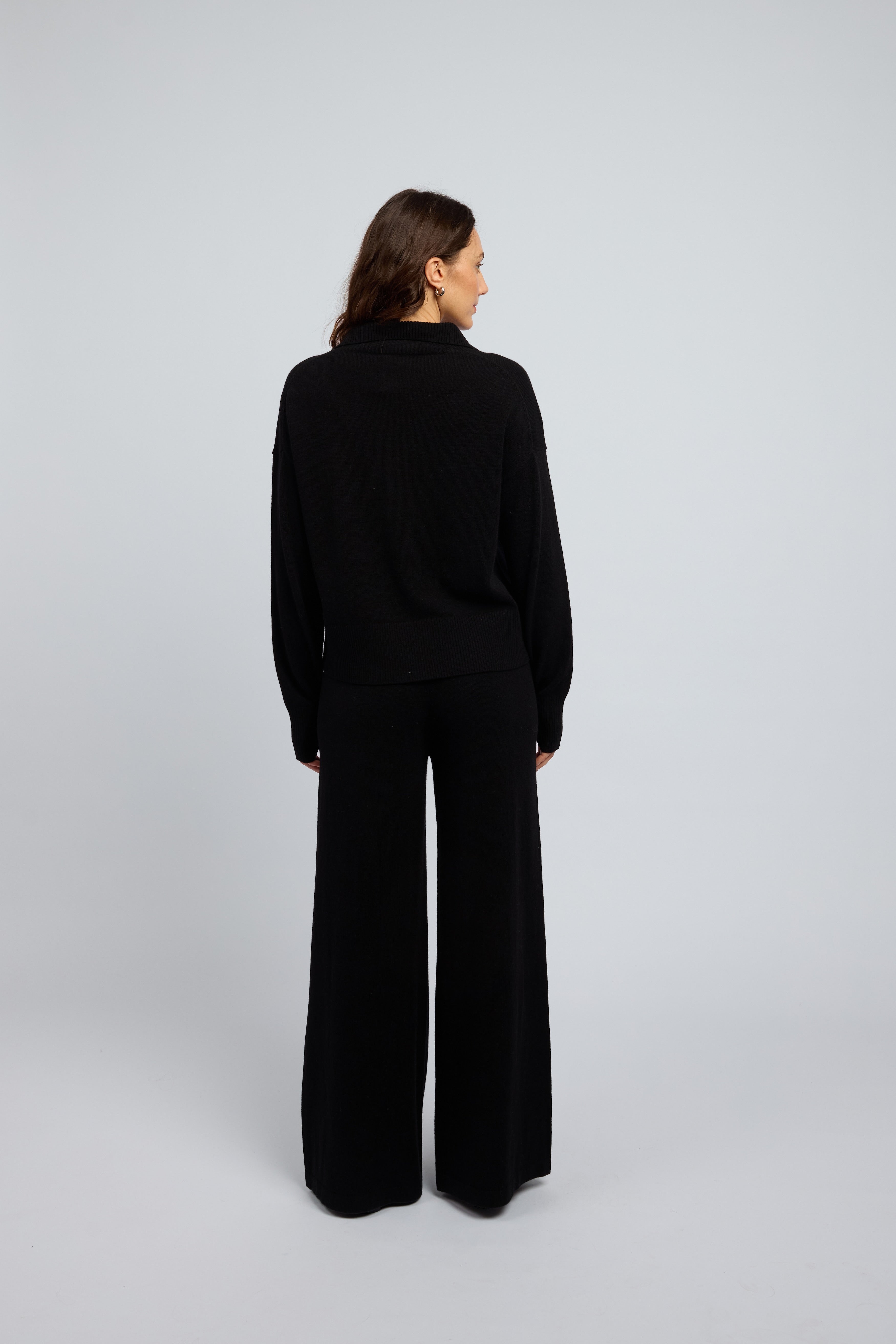 Woman wearing a cashmere set in black, matching pants and zip through jumper with a folded down collar