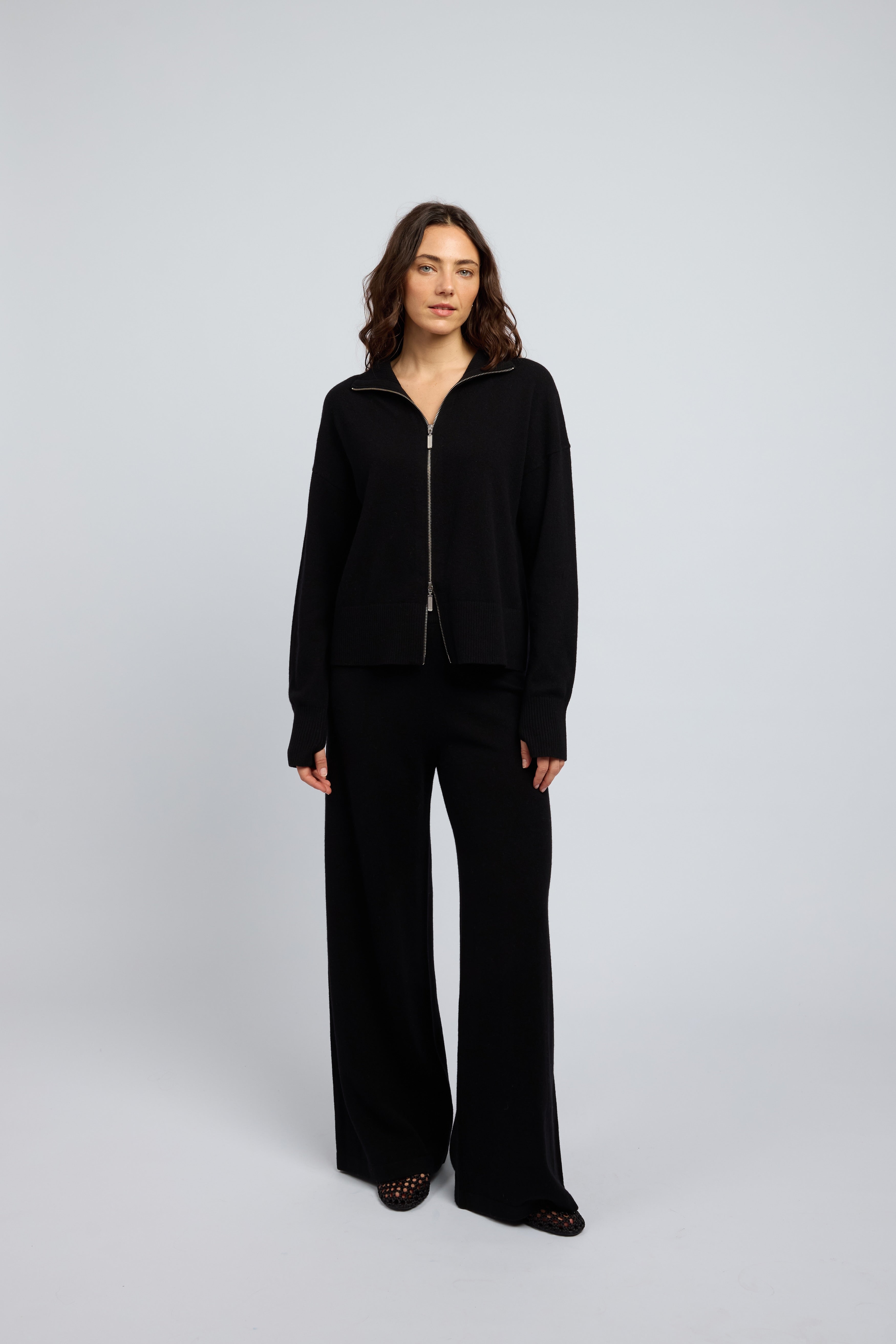 Woman wearing a cashmere set in black, matching pants and zip through jumper with a folded down collar