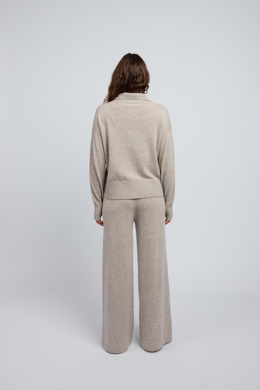 Woman wearing a cashmere set in grey marle, matching pants and zip through jumper with a folded down collar