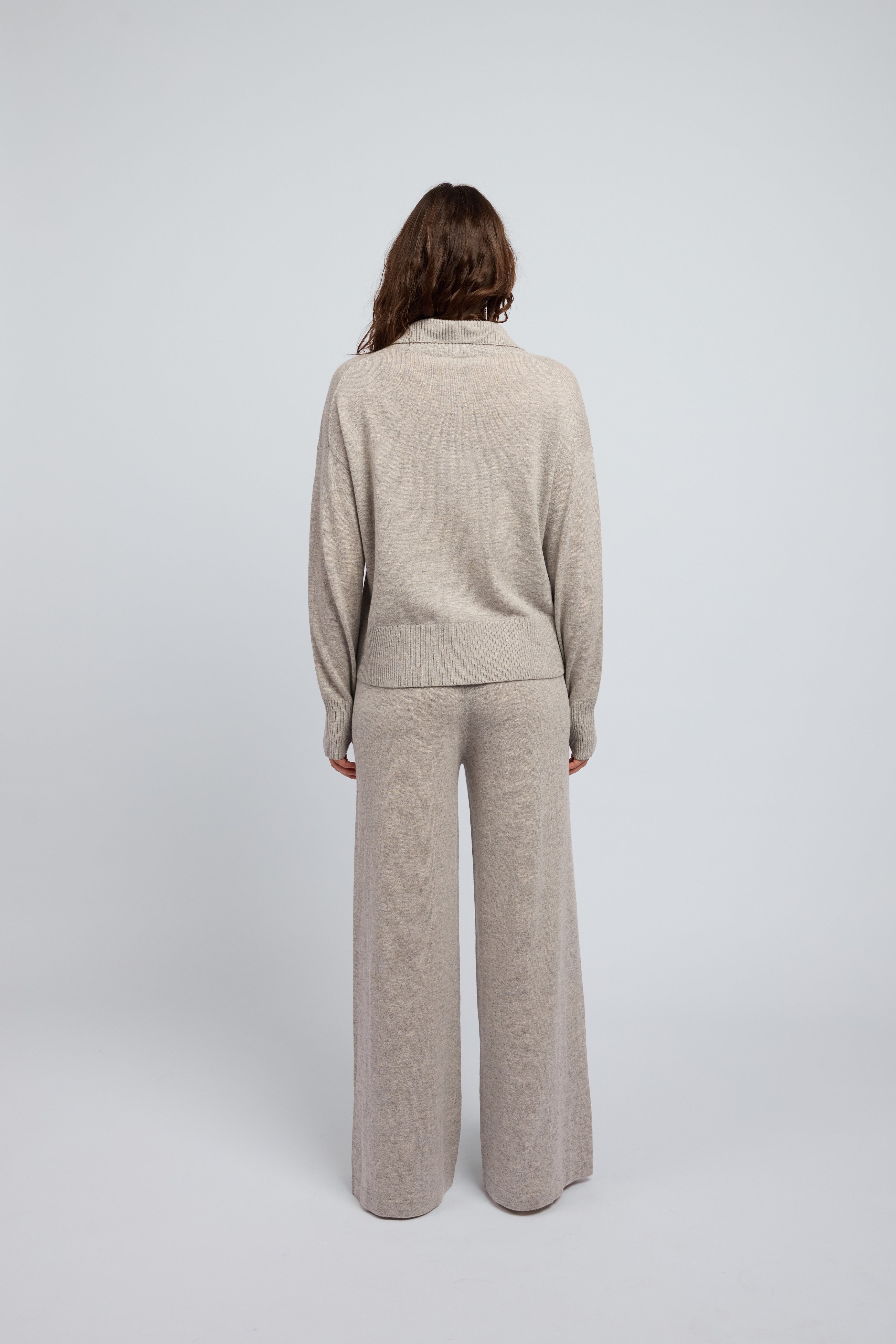 Woman wearing a cashmere set in grey marle, matching pants and zip through jumper with a folded down collar