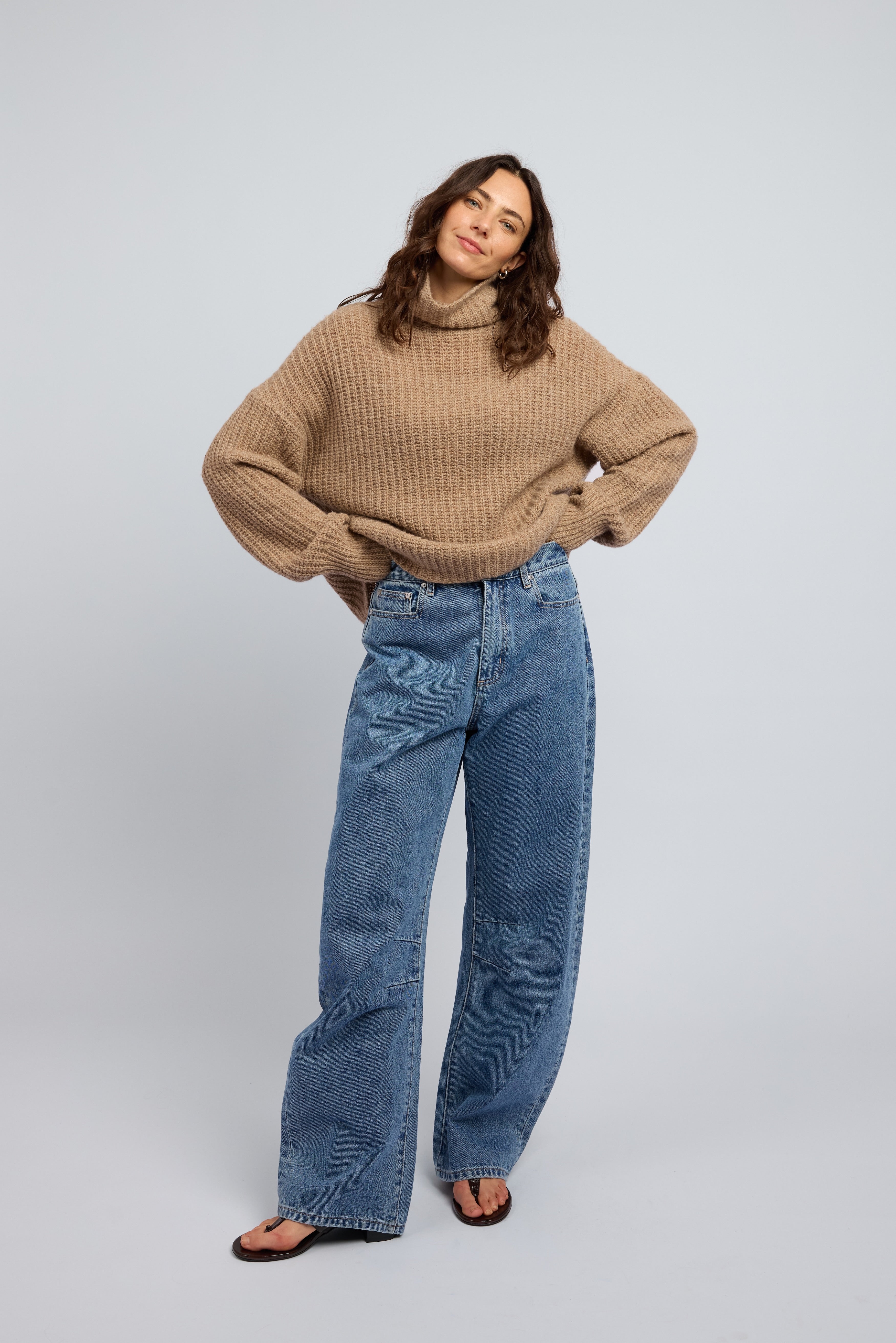 Woman wearing a beige cashmere sweater with turtleneck and blue jeans