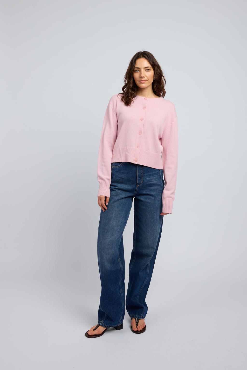 Bubblegum pink women’s cashmere cardigan styled with blue jeans and black thong heels